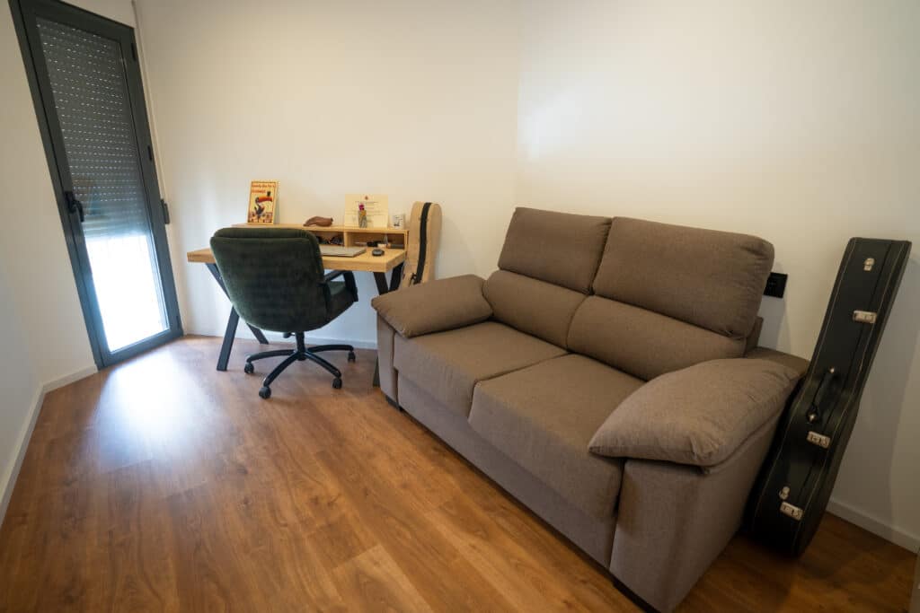Pequeña oficina con escritorio y sofá de dos plazas