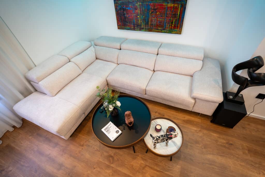 Sofá de tela esquinero con reposacabezas y mesa doble de centro con decoración