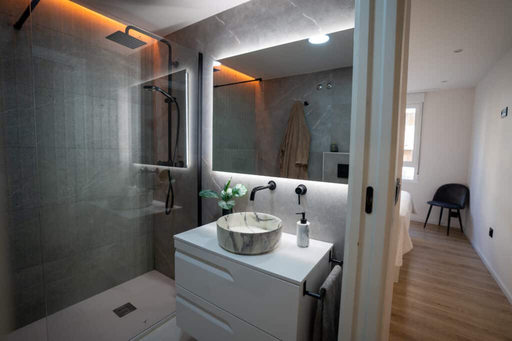 Baño con mampara fija y lavabo minimalista, espejo rectangular gigante con LED