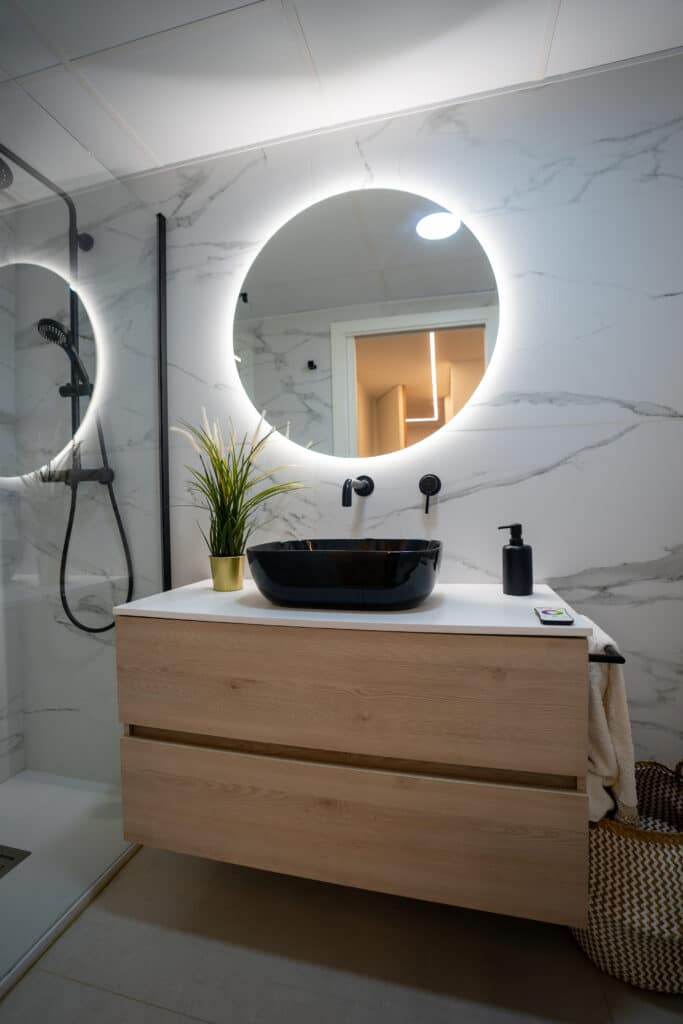 Espejo redondo con LED en baño y mueble de madera volado