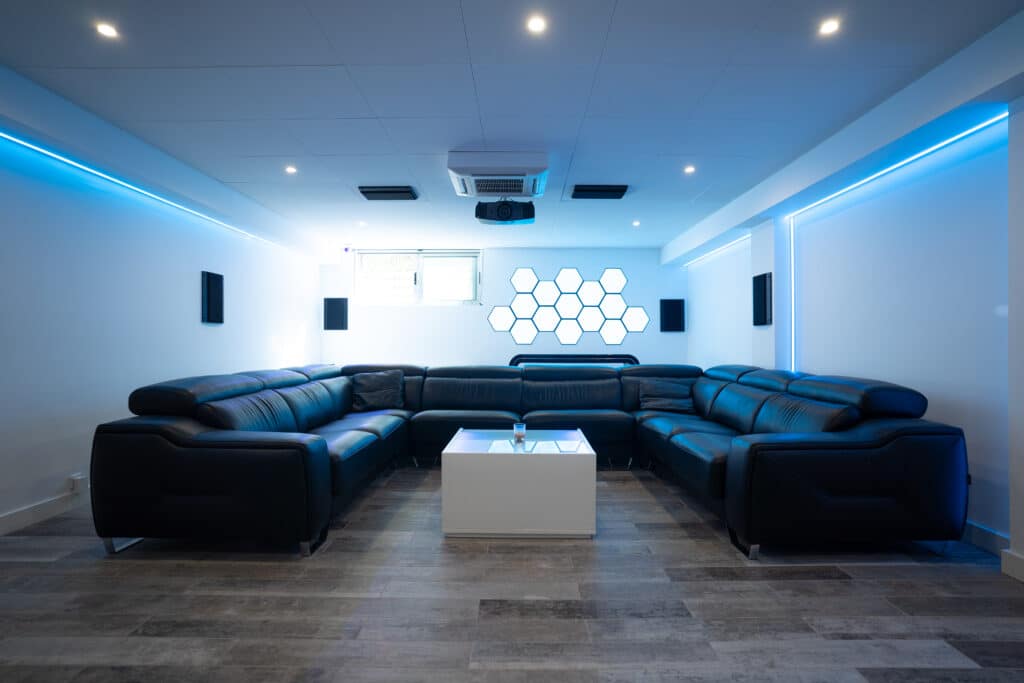 Sala de cine con proyector con sofá en forma de U con mesa cuadrada de centro