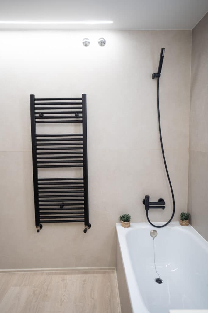 Bañera con grifo negro y secador de toallas