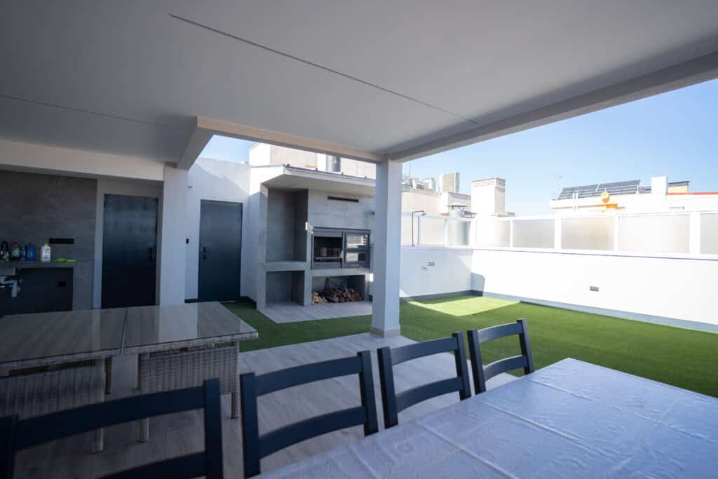 Barbacoa en terraza con césped artificial con sillas y mesa para comer