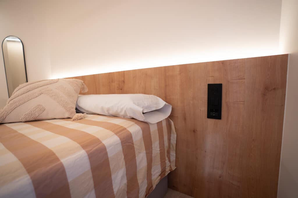 Cabecero de madera en la cama de matrimonio con iluminación LED