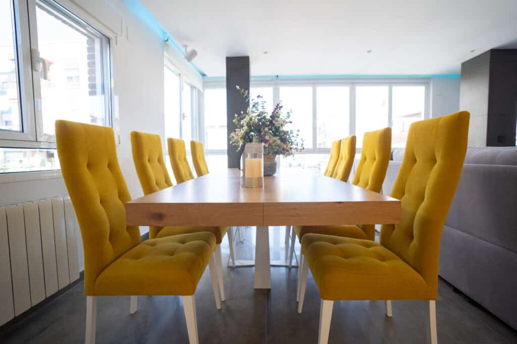 Conjunto de mesa larga de comedor con sillas de gran respaldo tapizadas con iluminación natural