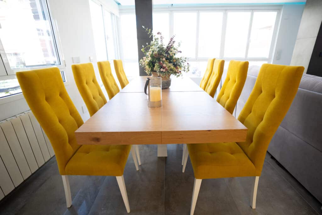 Conjunto de mesa larga de comedor con sillas de gran respaldo tapizadas y centro de mesa