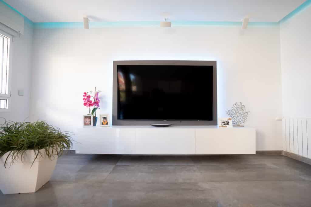 Televisión grande de salón en mueble volado blanco